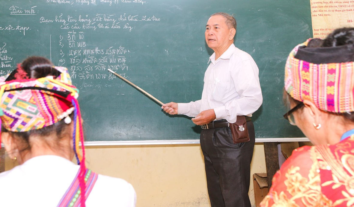 Ông Vi Khăm Mun trong một buổi đứng lớp truyền dạy chữ Thái - Ảnh: Đình Tuân