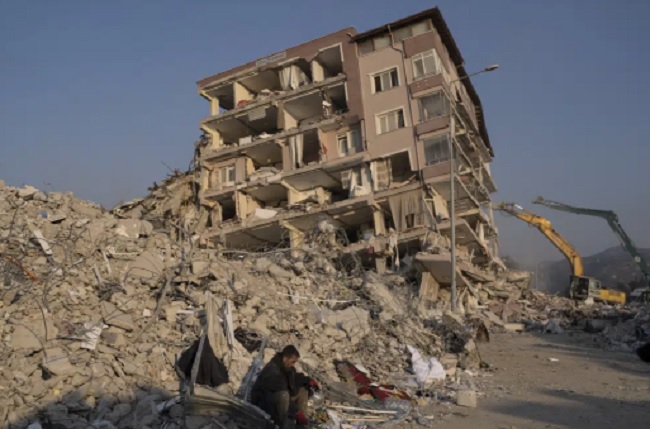 Một người đàn ông ngồi thẫn thờ trước đống đổ nát của tòa nhà bị đổ sập ở Antakya, Thổ Nhĩ Kỳ. Ảnh: AP