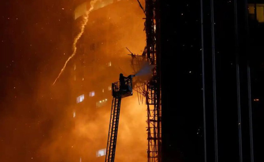Lính cứu hỏa đang xịt vòi rồng trực tiếp vào giàn giáo và tầng cao đang bốc cháy của tòa nhà (Ảnh: REUTERS)