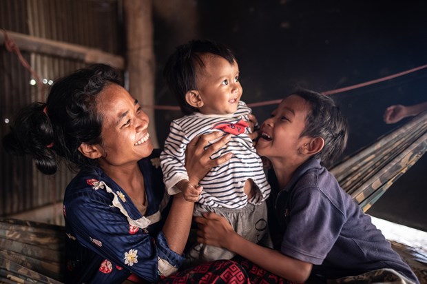 Hình ảnh em bé 10 tháng tuổi, sinh ra với bàn chân khoèo, chia sẻ khoảnh khắc vui vẻ với mẹ và anh trai trong ngôi nhà của gia đình gần Battambang (Campuchia) vào tháng 2/2023 (Ảnh: WABE)