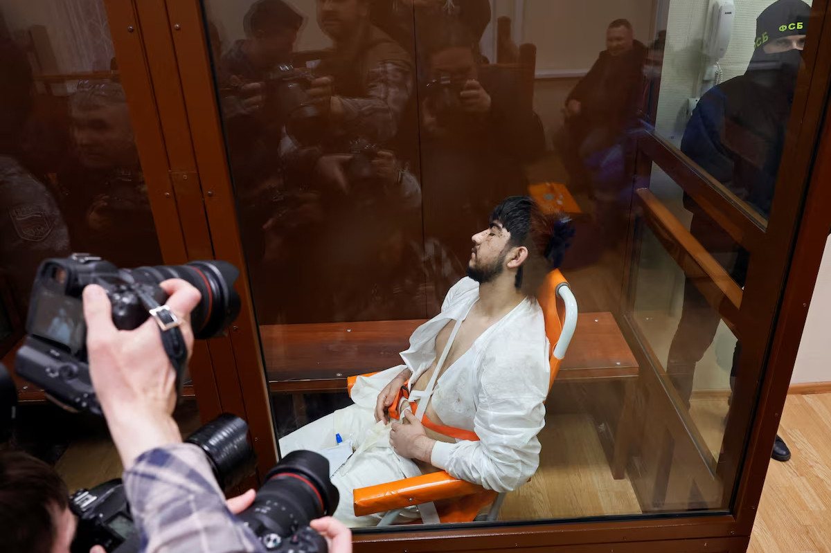 Nghi phạm Muhammadsobir Fayzov ngồi trên ghế vận chuyển y tế phía sau bức tường kính dành cho các bị cáo trước phiên tòa tại tòa án quận Basmanny ở Moscow, Nga ngày 24/3. Ảnh: Reuters