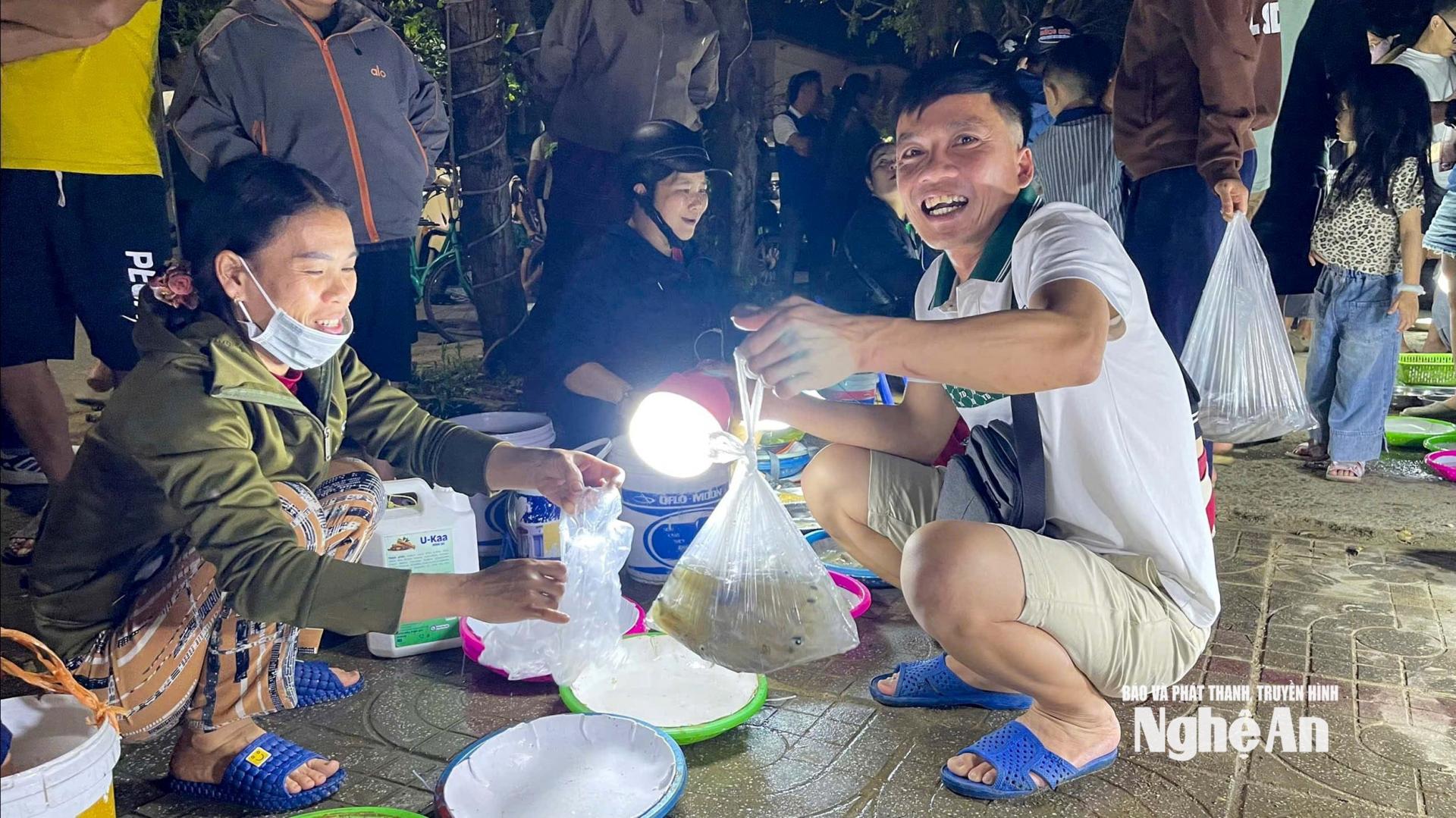 Anh Trần Xuân Trung (bên phải, áo trắng) vui vẻ khi mua được mớ mực tươi vừa ý. Ảnh: Đình Tuyên