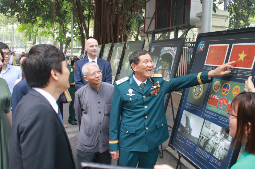 Trung tướng Phạm Tuân và hình ảnh 2 lá cờ được ký trong vũ trụ trên chuyến Soyuz-37. (Ảnh: Minh Anh/Vietnam+)