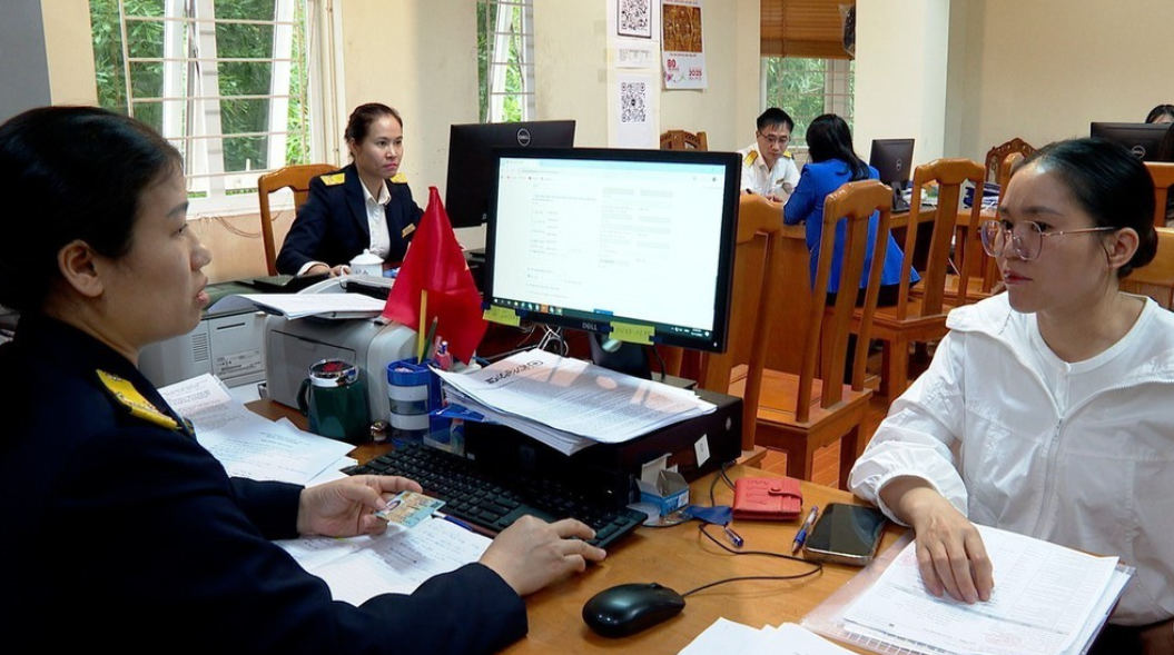 Cán bộ Thuế hướng dẫn hộ kinh doanh chuyển đổi mô hình từ thuế khoán sang kê khai. Ảnh: Nguyễn Thảo - TTXVN