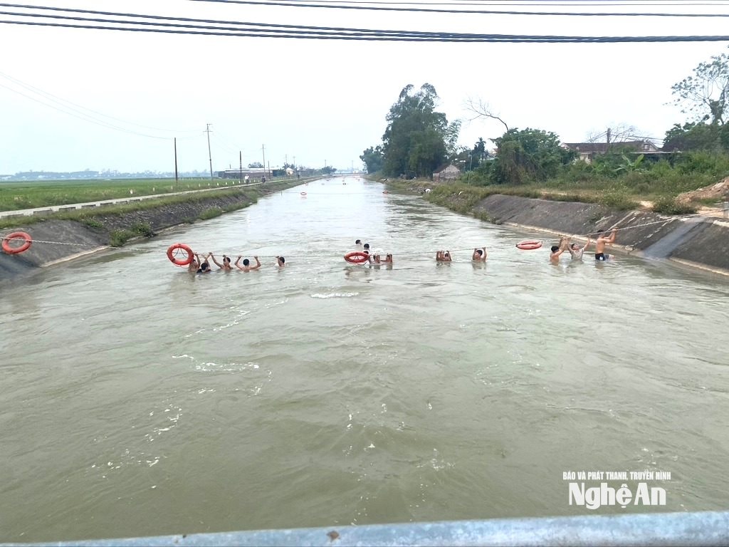 Trẻ em đu mình trên dây xích phao ở kênh đào. Ảnh: Văn Trường