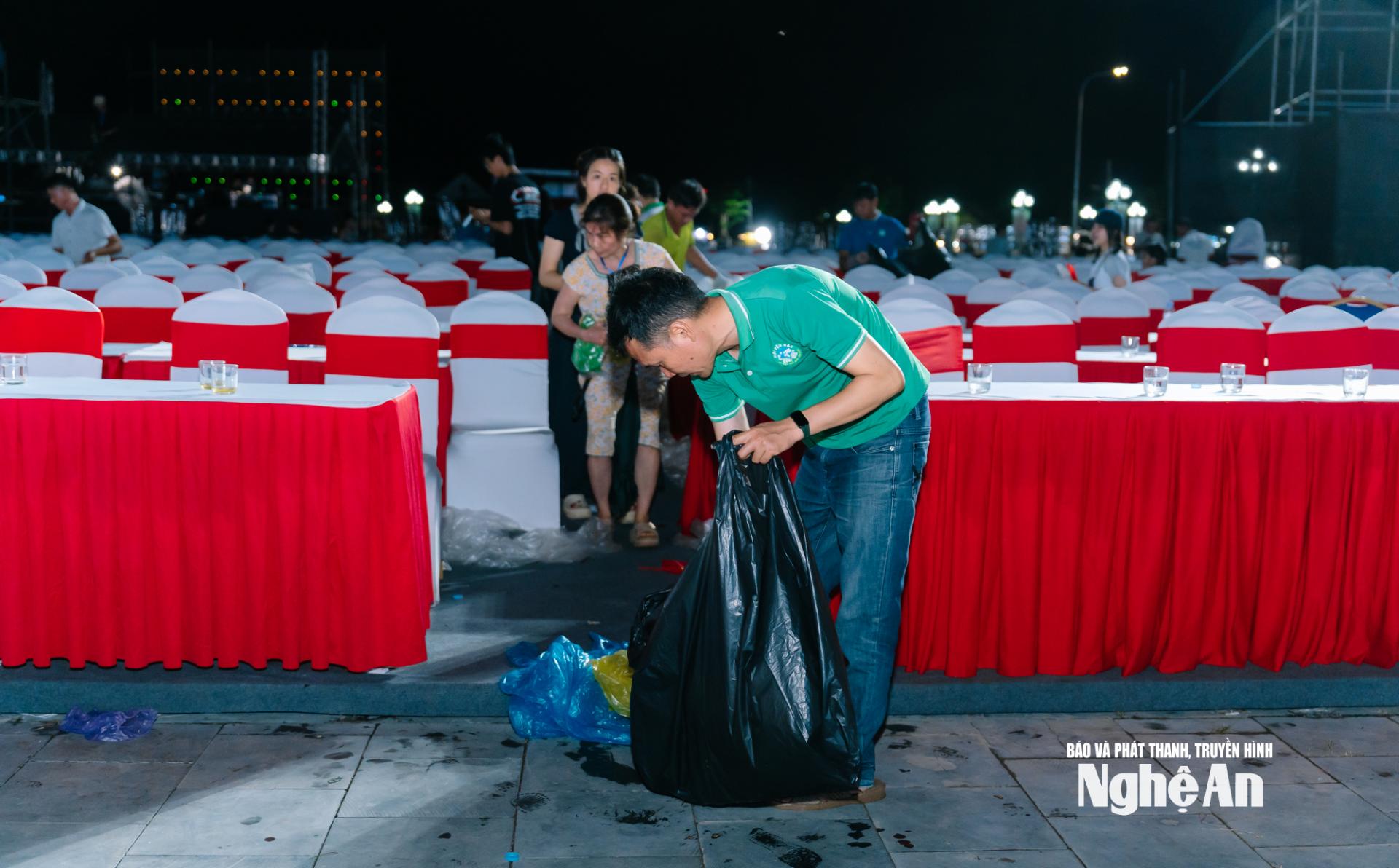 Dưới ánh đèn đêm sau lễ khai mạc, các tình nguyện viên tỉ mỉ nhặt từng mẩu rác nhỏ, trả lại sự sạch đẹp cho khuôn viên Làng Sen.