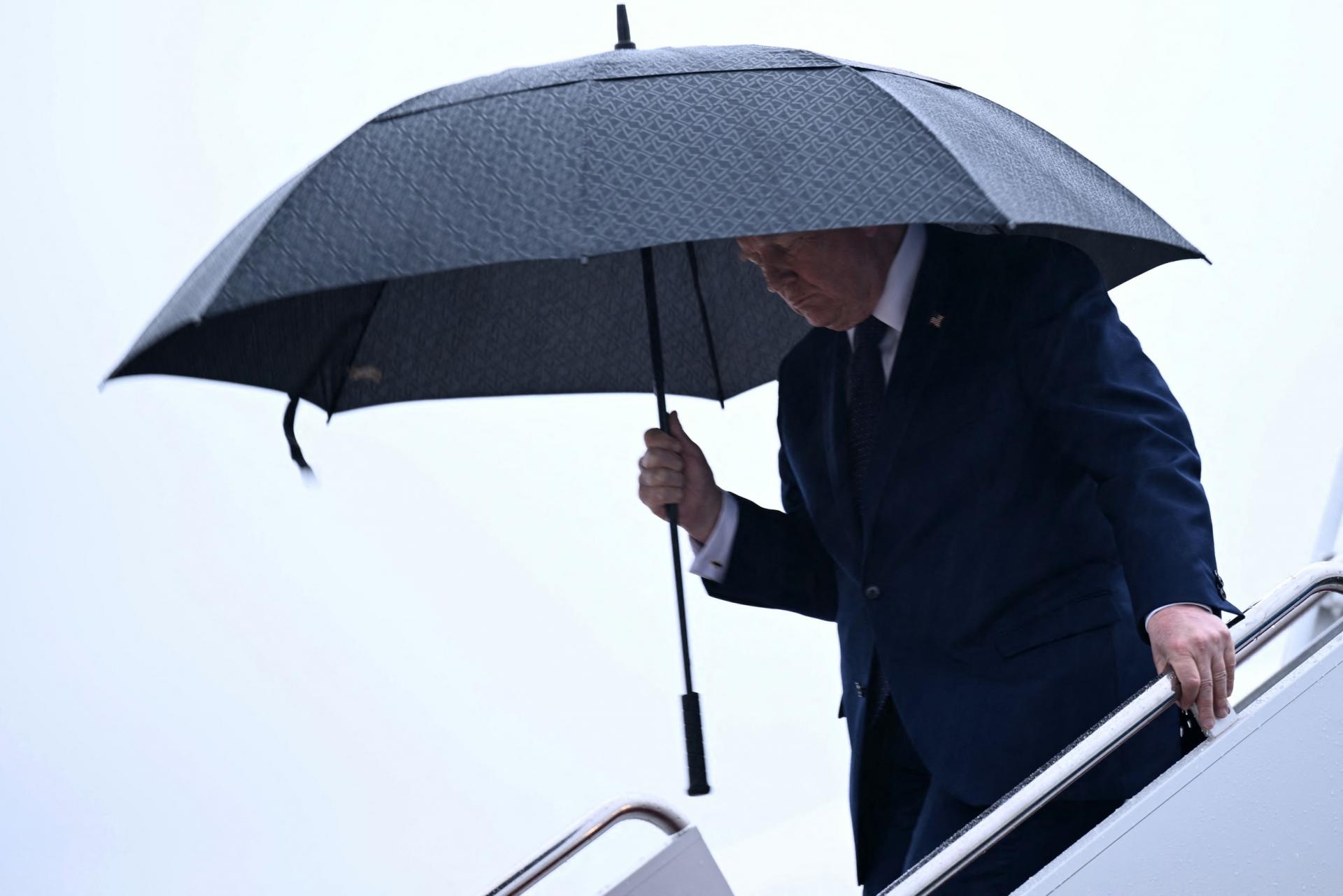 Tổng thống Mỹ Donald Trump che ô bước xuống chuyên cơ Không lực Một tại Căn cứ Liên hợp Andrews (bang Maryland) ngày 22/5, chuẩn bị trở lại Nhà Trắng sau chuyến công tác và phát biểu tại New York. Ảnh: AFP