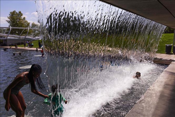 Người dân tránh nóng bên đài phun nước tại Washington, D.C., Mỹ, ngày 11/7/2023. Ảnh: THX/TTXVN