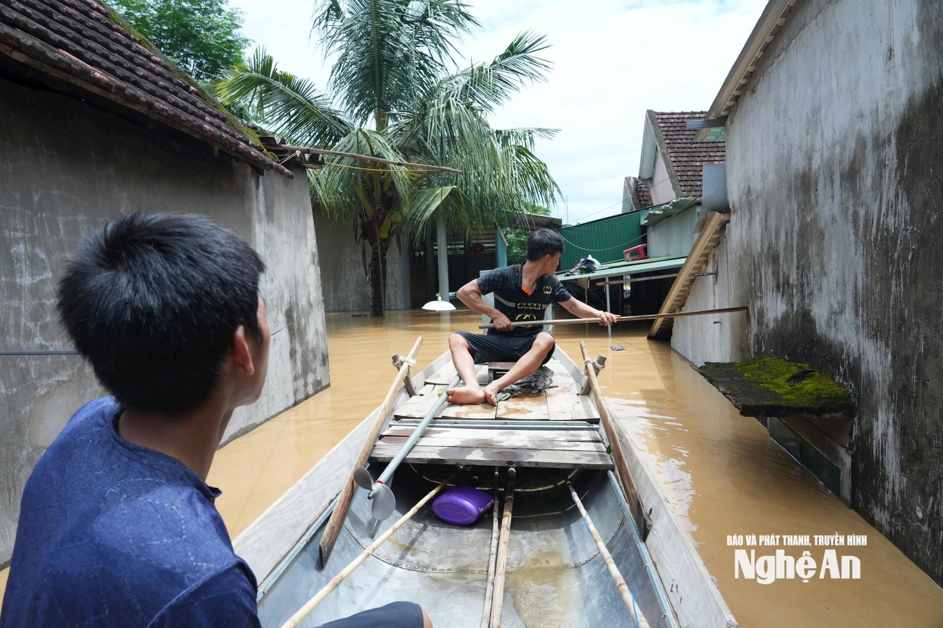 Trong sáng 23/7, người dân sử dụng thuyền tìm cách vớt lấy những tài sản chưa kịp di dời trong đêm. Ảnh: Thành Chung