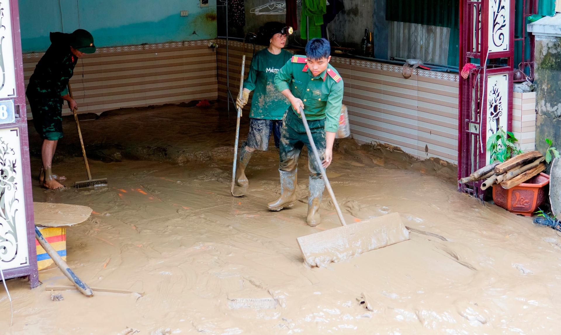 Lực lượng quân sự, công an đang hỗ trợ người dân dọn dẹp vệ sinh môi trường. Ảnh: Phạm Bằng