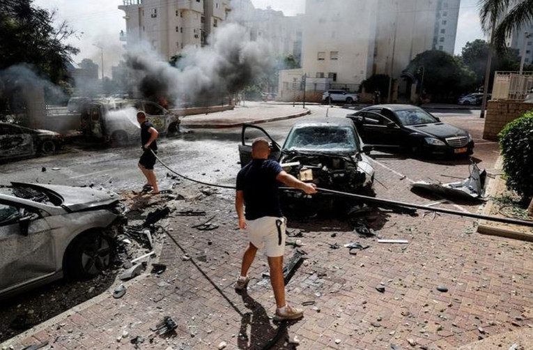 Người dân Israel nỗ lực dập lửa ở TP Ashkelon, một trong những nơi trúng nhiều rốc-két bắn từ Gaza hôm 7-10 Ảnh: REUTERS