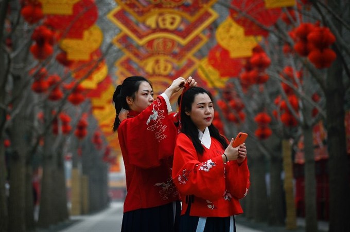 Phụ nữ mặc trang phục truyền thống Trung Quốc chỉnh lại tóc để chụp ảnh trong công viên ở Bắc Kinh hôm 2/2.