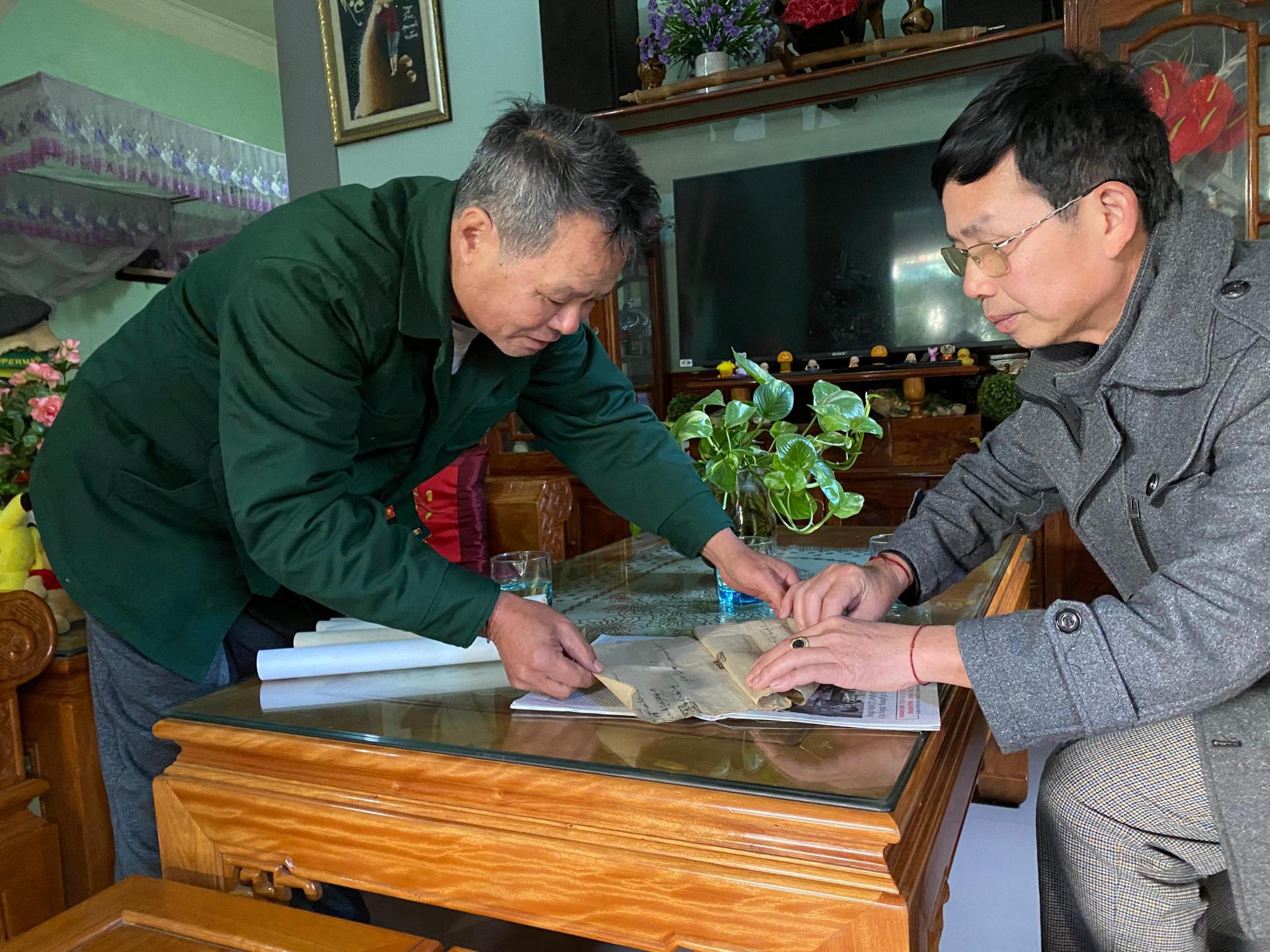 Ông Vi Tân Hợi (bìa phải) và thầy Lô Văn Thông giới thiệu về tờ khế ước cổ.