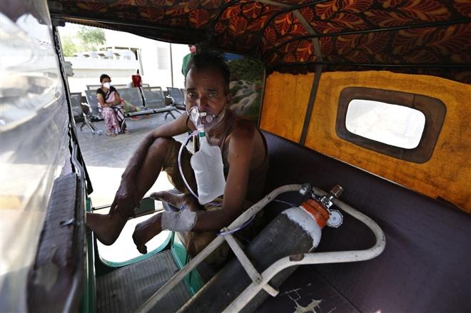 Bệnh nhân COVID-19 thở bằng mặt nạ oxy trong khi chờ nhập viện ở Ấn Độ. (Ảnh: AP)