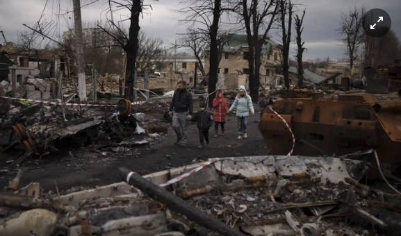 Một gia đình đi bộ giữa khung cảnh tan hoang ở Bucha, ngoại ô Kyiv, Ukraine. Ảnh: AP.