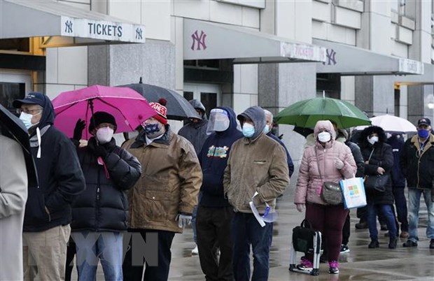 Người dân đeo khẩu trang phòng lây nhiễm COVID-19 tại một điểm tiêm chủng ở Mỹ. (Ảnh: AFP/TTXVN)