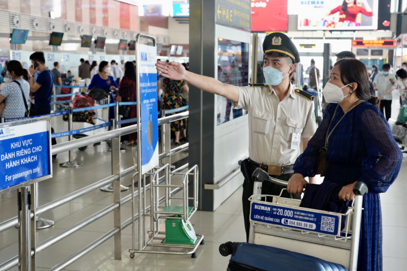 Nhân viên an ninh sân bay hướng dẫn hành khách vào khu vực làm thủ tục trước khi bay.