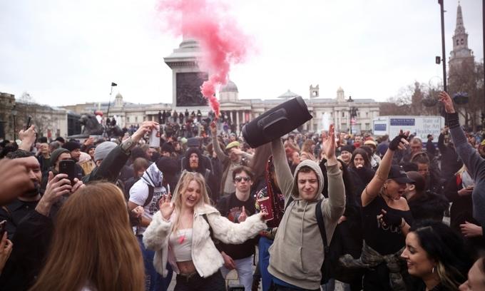 Người dân nhảy nhót, đốt pháo sáng khi biểu tình chống phong tỏa ở London, Anh, hôm 20/3. Ảnh: Reuters.