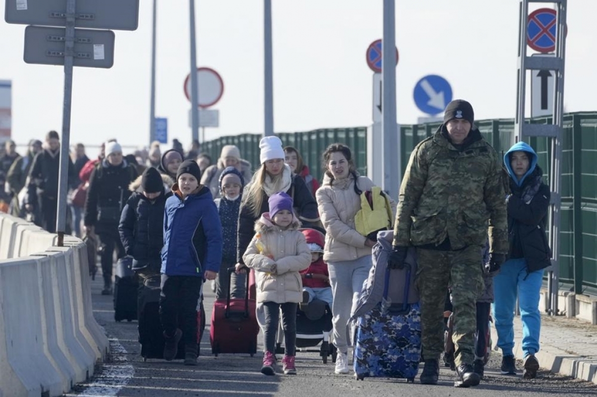 Một lính biên phòng Ba Lan hỗ trợ người tị nạn Ukraine khi họ vừa qua cửa khẩu Korczowa.