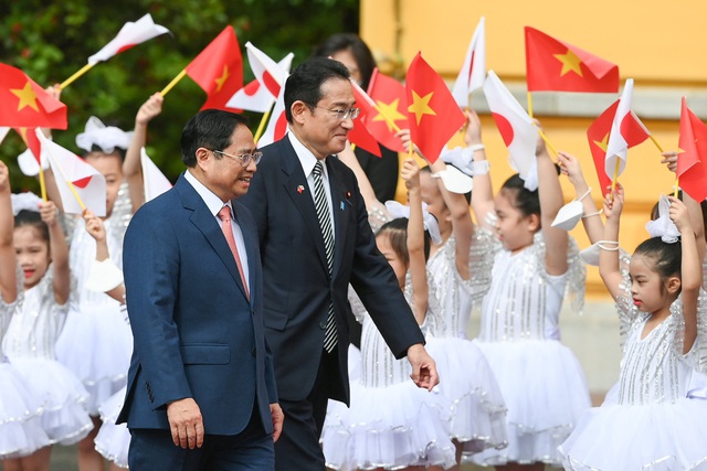 Thủ tướng Phạm Minh Chính mời Thủ tướng Kishida Fumio bước trên thảm đỏ trong tiếng vẫy chào của các em học sinh. 