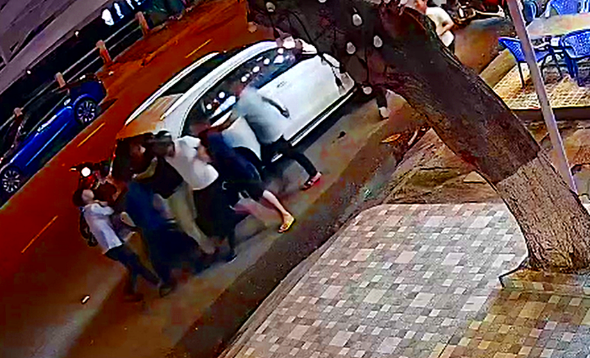 Nam và người bạn mắc áo trắng đội nón bảo hiểm bị đánh đập, hành hung. Ảnh cắt từ camera.