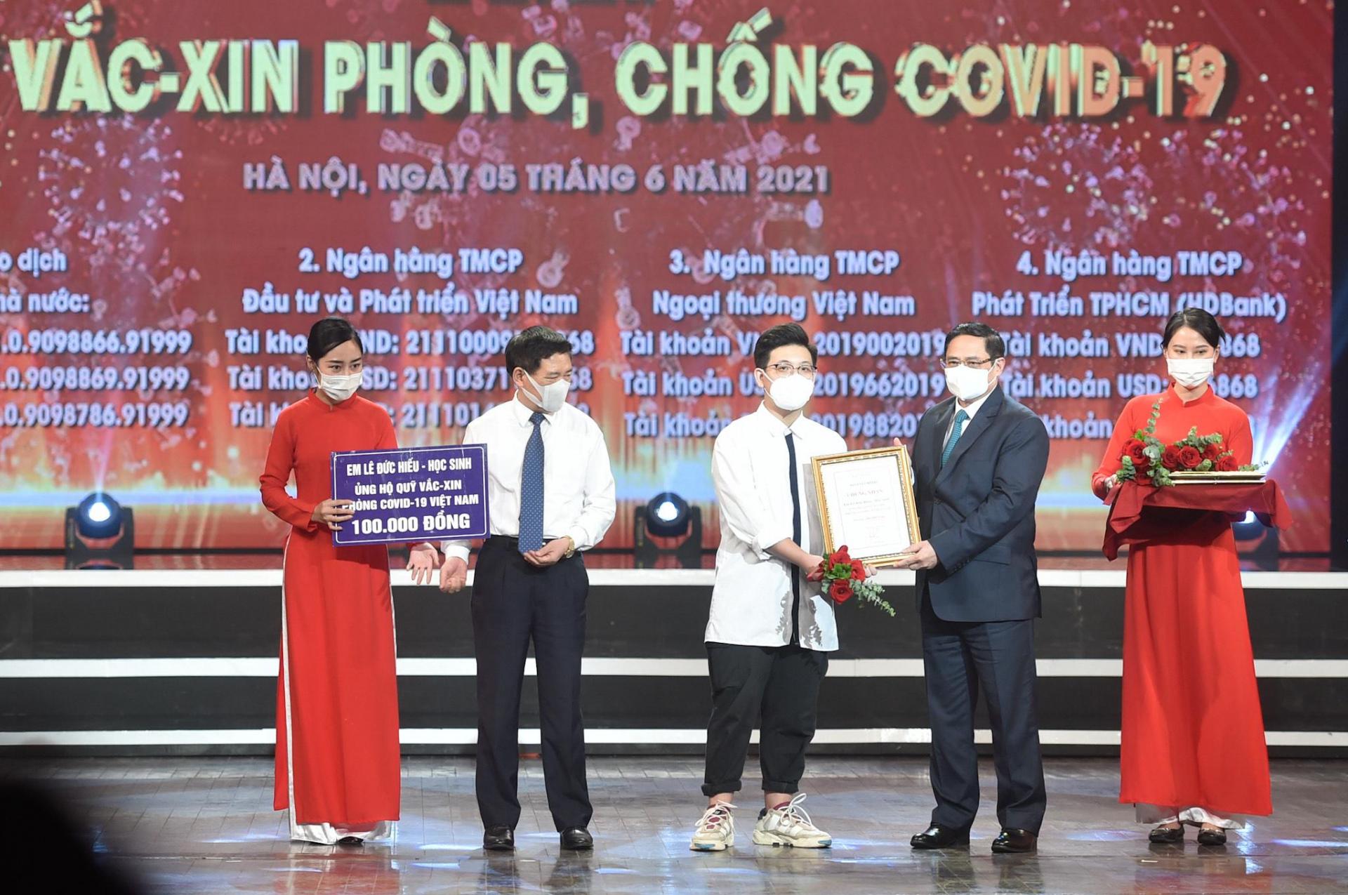 Thủ tướng Chính phủ Phạm Minh Chính trao chứng nhận, hoa cảm ơn em Lê Đức Hiếu, học sinh Trường Phạm Hồng Thái, Ba Đình, Hà Nội, 15 tuổi. 