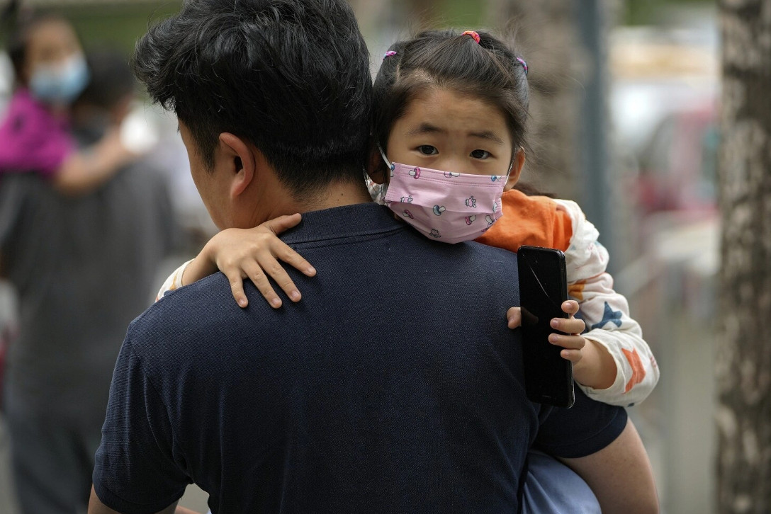 Một phụ huynh bế con gái đến trường ở Bắc Kinh, Trung Quốc. Ảnh: Andy Wong/Associated Press.