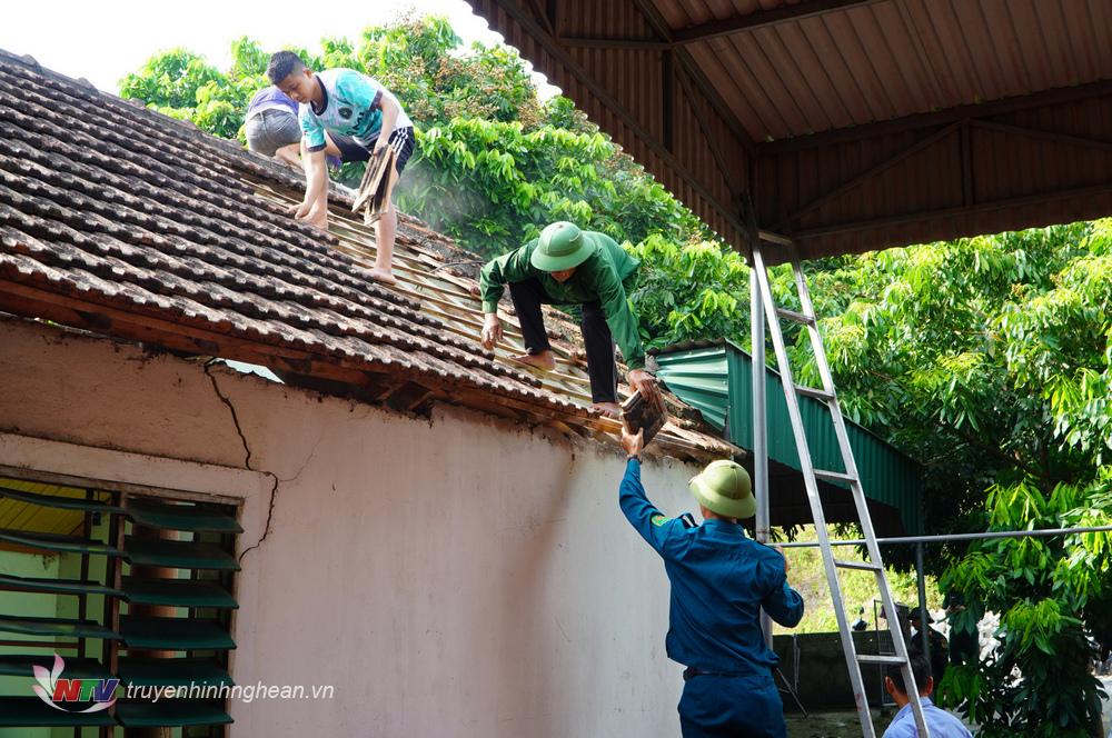 Lực lượng dân quân Ban Chỉ huy Quân sự huyện, cùng bà con nhân dân giúp bà tháo dỡ ngôi nhà để xây nhà mới.