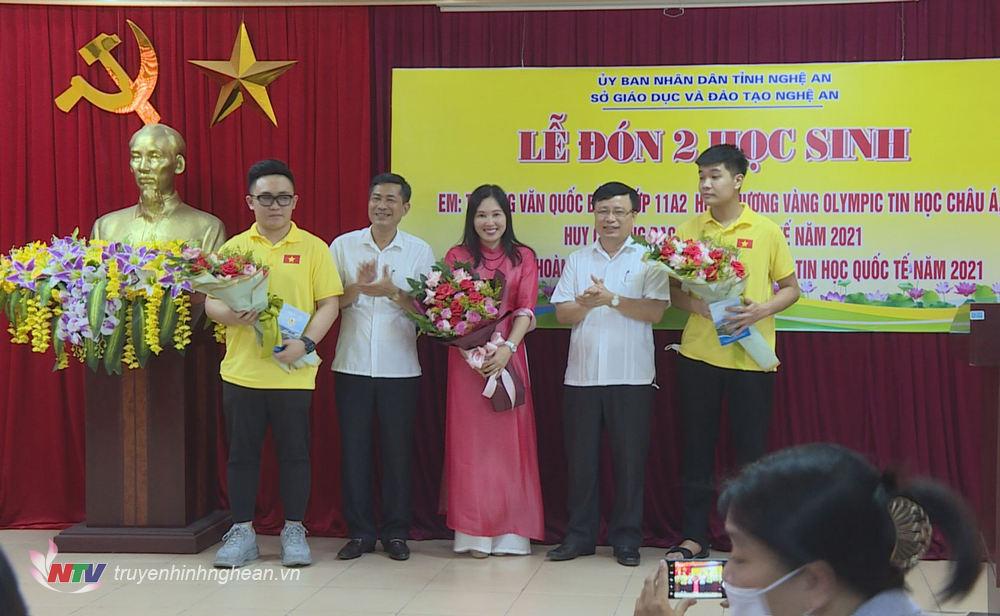 Phó Chủ tịch UBND tỉnh Bùi Đình Long và Giám đốc Sở Giáo dục - Đào tạo Thái Văn Thành tặng hoa chúc mừng 2 học sinh.