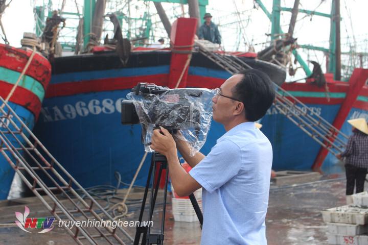 Phóng viên Song Thi bảo vệ máy móc để có những hình ảnh đẹp, sinh động khi mưa bão bắt đầu đổ bộ vào bờ