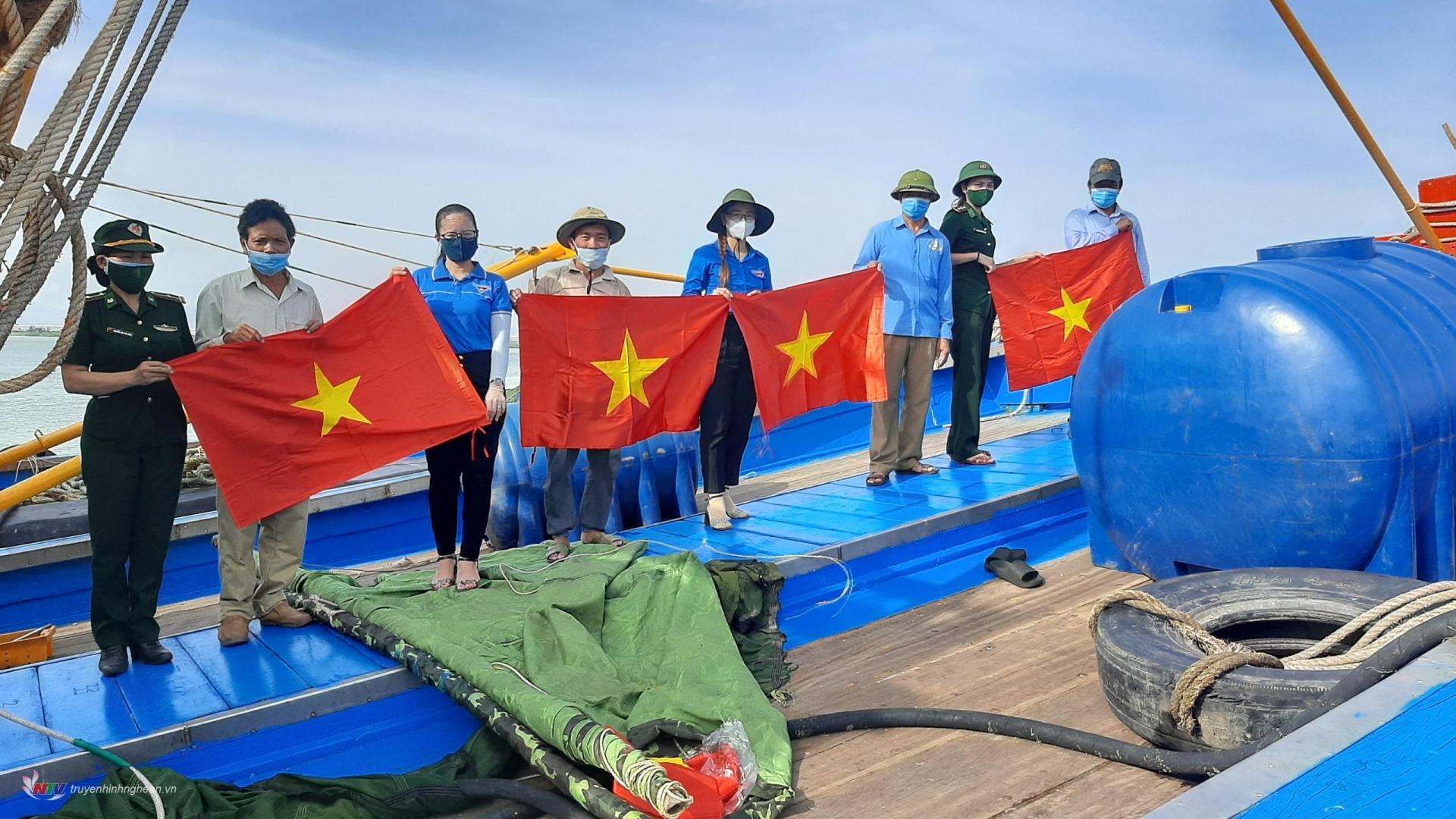 Hội viên phụ nữ Hải đội 2, Hội phụ nữ BĐBP tỉnh Nghệ An phối hợp phụ nữ địa phương tặng cờ Tổ quốc cho ngư dân vươn khơi bám biển