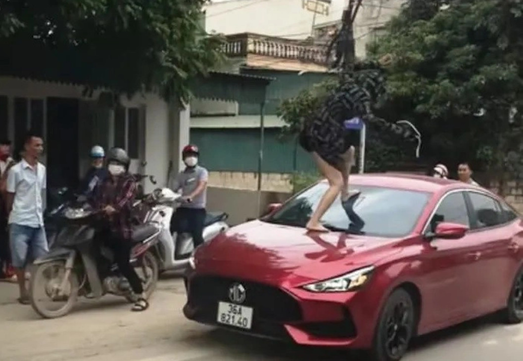 Người phụ nữ nhảy lên đầu xe ô tô đạp vỡ kính: Ảnh: Cắt từ clip).