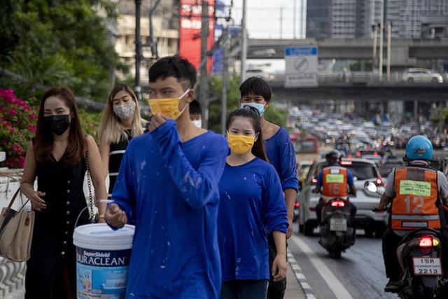 Người lao động Thái Lan đeo khẩu trang đi trên vỉa hè ở Bangkok. (Ảnh: AP)