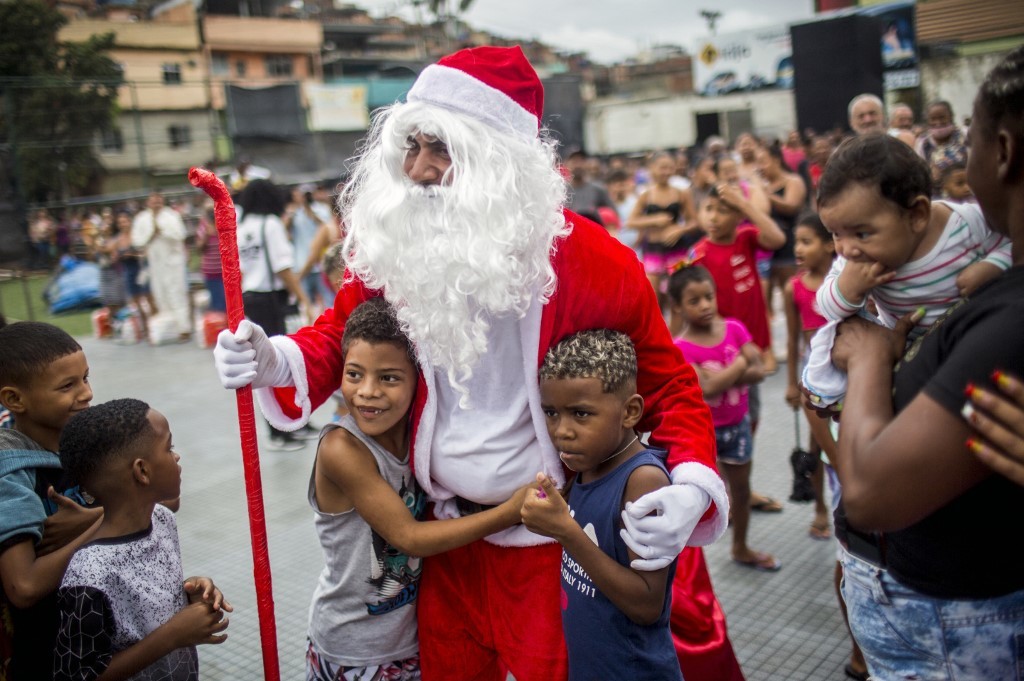 Trẻ em chào đón Ông già Noel tới phân phối suất ăn từ thiện ở khu phức hợp Alemao, Rio de Janeiro, Brazil, ngày 23/12.